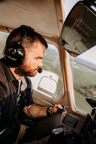 A male pilot with headset navigates a small aircraft in flight, capturing a focused cockpit environment.