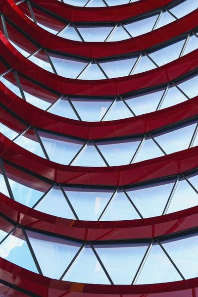 Dynamic red and glass architectural facade with geometric patterns in a modern style.